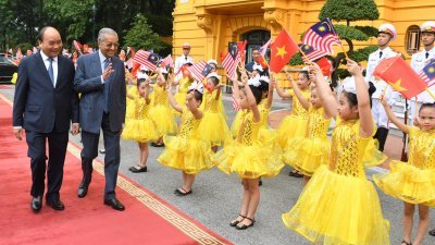 在越南展开官访的马哈迪（左2）出席官方迎接仪式，向在场由多名小孩组成的迎宾队伍挥手。左为越南总理阮春福。

