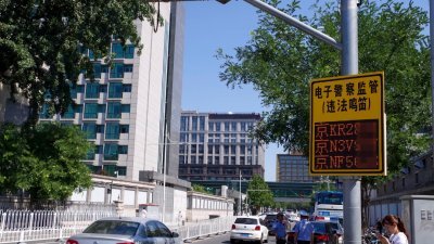 这是北京市东城区街上的监视器，在抓拍违法鸣笛车辆。这些监视器被称为“电子警察”，是一种交通违法抓拍系统，从定位、识别图像车牌并显示在电子屏上，整个过程只有几秒钟。