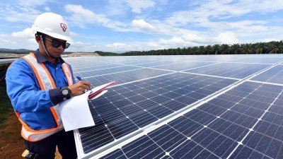 在武吉士南卯大型太阳光伏电站项目，一名员工在检察太阳光伏电板。