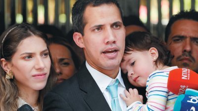 自行宣誓为委内瑞拉临时总统的反对党领袖瓜伊多（中），与支持者召开会议和提出反对派政府的计划后，在其住家外抱著女儿，向媒体发言。瓜伊多妻子法比亚娜陪伴在侧。