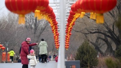 今年，中国不少城市发出了少放鞭炮的呼吁。在政府和民众的共同努力下，环保过大年正逐渐成为被人们接受的生活方式。这是游客在红灯笼装饰的北京玉渊潭公园揽玉桥参观游览。