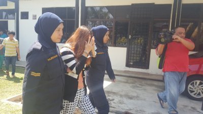 身穿黑白色条文衣服的越南籍女被告，周三上午在警方押送下抵步丰盛港推事庭，面对媒体镜头时，以双手掩面。