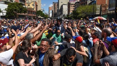 自立为临时总统的委内瑞拉反对派领袖瓜伊多（中）在周二离开集会现场时，被支持的群众包围。瓜伊多宣布，救援物资将于下周六送入委内瑞拉。