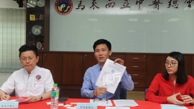 郭伟康（中）向媒体展示马来西亚中医总会所发出的中医行医证。左起为林迪 卫及颜晓雯。 （摄影：徐慧美）