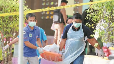 泰国北大年府一所学校的4名志愿警卫人员，周四遭到8名闯入校园的武装分子开枪打死。图为医务人员正将遇害的警卫人员尸体抬走。