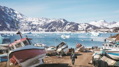 全球暖化加速了格陵兰岛冰盖的融化，也导致该海域的鱼种慢慢丰富了起来，为岛上渔民捎来商机。一名男子徒步经过搁浅在西拉克镇岸边，等待出海的渔船。