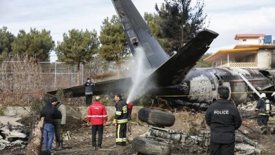 一架波音707的军用运输机在伊朗首都德黑兰西部坠毁，消防人员正在运输机的残骸旁，扑灭火势。