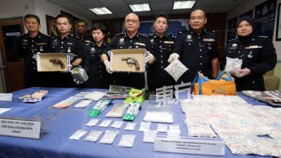 卢卡斯（左4）与麻坡及峇株巴辖两个警区的肃毒组调查官展示，警方在行动中起获的毒品及军火。 （摄影：刘维杰）