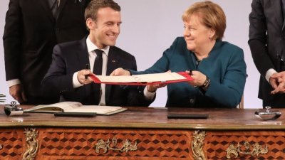 法国总统马克龙与德国总理默克尔在签字仪式上，交换法德友好条约。