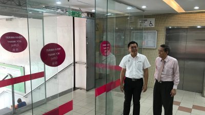 郑来兴（左起）与洪祖丰指光大入口处安装玻璃门，阻挡建筑外的热气流入建筑内，成功省下数十万令吉电费。