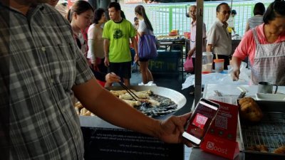 灵市SS2巴刹为州内首个采用电子钱包的巴刹区，图中黄思汉试用电子钱包支付方式。