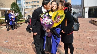吴馨瑜父母在毕业典礼上，开心地亲吻吴馨瑜。
