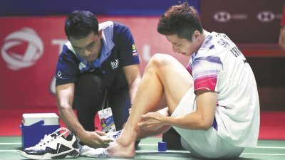中国选手石宇奇（右）周四晚在印尼羽球超级1000赛男单次圈，与丹麦选手安东森的比赛中崴脚，因伤退赛。