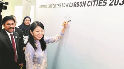 杨美盈（右）为2030年低碳城市挑战主持推介后，在看板上签名。左为赛阿曼。
