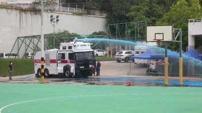 香港一辆水炮车正在粉岭机动部队总部操场内进行测试，只见车顶的喷射器，朝一个方向发射出强力的蓝色水柱，威力巨大。