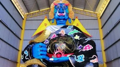 默贡斗母宫盂兰胜会今年大士爷的金身，脸部以蓝色荧光颜料彩绘、身穿黑色龙袍、左手握火球，右手放在膝盖上亮相。
