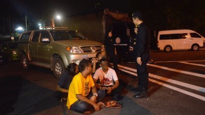 4名外籍劳工被陆路交通局官员截停后，坐在路边等待进一步行动。
