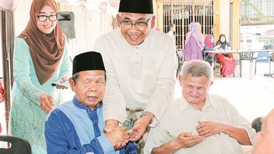 阿都阿兹巴里（中）在马来西亚视障人士协会霹雳分会的开斋节活动，派发青包给出席的会员。