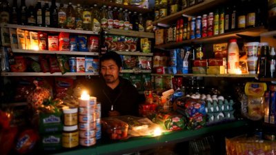 由于电力互联系统瘫痪，导致阿根廷周日全国大范围停电。一名在阿根廷首都布宜诺斯艾利斯经营杂货店的民众，于停电期间点燃蜡烛，并在微弱的火光下继续营业。