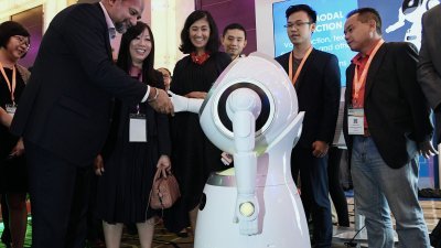 哥宾星（左）在大马科技周开幕后参观展览时，于展示会上引人注目的机器人握手。左2起为连美玲、苏里娜。