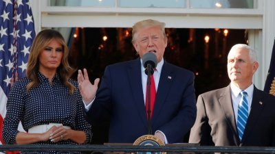 美国总统特朗普（中）在夫人马拉尼亚（左）及副总统彭斯的陪同下，在白宫南草坪举行的年度“国会野餐”活动上讲话。