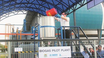 曹观友将厨余倒进峇都茅厨余沼气发电厂的设施里，通过此项科技作进一步处理。