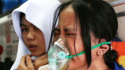 一名受空气污染影响的努沙达迈国中女学生，因身体不适而露出痛苦的表情，令人心疼。