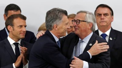 阿根廷总统马克里（左2）周六在日本大阪举行的G20峰会新闻发布会上，拥抱欧盟委员会主席容克（右2）。左为法国总统马克龙。