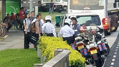 新加坡陆交局执法人员在马西岭地铁站附近的一个巴士站截查一辆汽车，司机涉嫌在没有执照的情况下载客来往马新两地。（取自网络）
