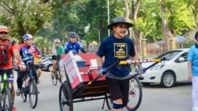谢志文顶著炎热的气候，以人力拉车的方式从槟城徒步到吉隆坡，全长400公里。