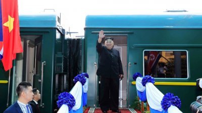 朝鲜最高领导人金正恩周六在越南同登火车站登上专列前，向欢送他的群众挥手告别。