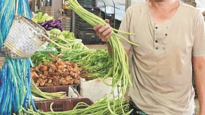 菜贩李锦源透露，天气干旱导致蔬菜价格上涨，图为他展示每公斤售价达8令吉50仙左右的菜豆。