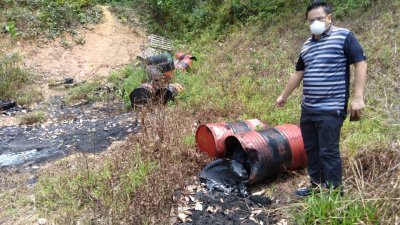 甘邦避兰东峇鲁百万镇培华二小附近出现非法丢弃化学物。图为陈传平手指装有黑色化学物体的桶。