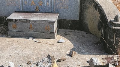 遭人破坏的石碑被丢弃在坟墓前。