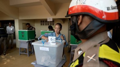 在南部陶公府的一所投票站，驻守的警员正看著一名穆斯林妇女投票。在局势不稳的泰南，当局禁止摩哆和汽车接近投票站，以防发生炸弹袭击等事件。