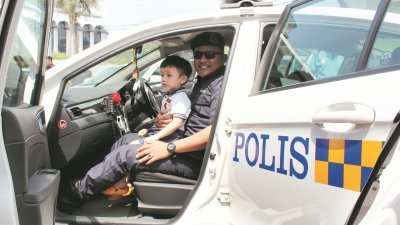 一名孩童在警员的陪伴下，体验乘坐警方巡逻车到邻近社区巡逻。