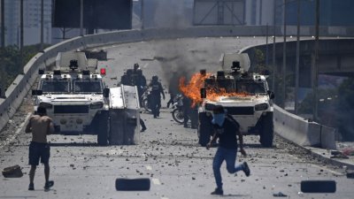 委内瑞拉首都加拉加斯街头在周二成为战场，军方出动装甲车镇压支持反对派的民众。