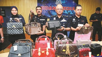 法米（右2）在立功下属的陪同下，向媒体展示由警方所起获的二手名牌手提包。
