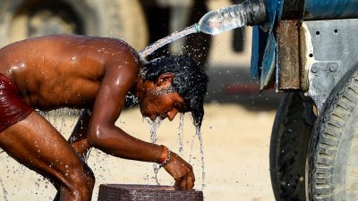 印度近日遭受热浪侵袭，国内大部分地区上周六录得接近摄氏50度高温。这是在北方邦安拉阿巴德，一名耐不住酷热天气的货车司机用水槽车的水来降低体温。