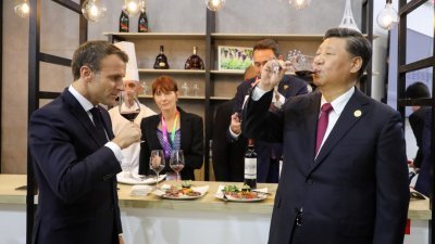 中国国家主席习近平（右）与法国总统马克龙（左），周二在参观上海进博会的法国馆时，一同品尝红酒。