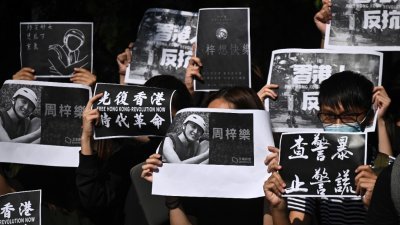 群身穿黑衣的香港科技大学学生手持标语和周梓乐的照片，游行到科大校长史维的住所。
