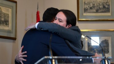 西班牙看守首相桑切斯（左）在与极左“我们可以”党领袖伊格莱西亚斯会面时拥抱。双方达成初步协议，有望打破长达数月的政治僵局。
