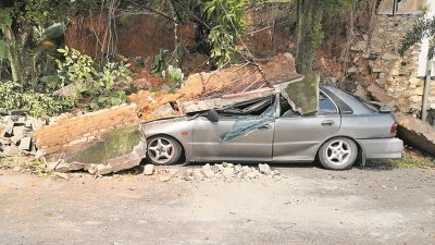 防崩墙塌陷，沙石压垮停放在斜坡旁的国产轿车。