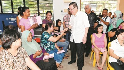 林冠英（站者右）于周日在峇眼国会选区发放乐龄人士回馈金、单亲妈妈及黄金妈妈援助金的活动上，向受惠者嘘寒问暖。
