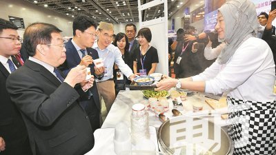 陈国伟（左起）和白天在周一出席在吉隆坡国际展览中心举行的亚洲自有品牌贸易展以及陕西特色商品展览会上，品尝来自中国陕西省的道地食物。（摄影：张真甄）