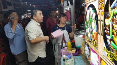 陈俊良（左2）出示照片证明本身曾拜访过受影响的柔佛再也美食街小贩。
