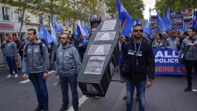 参与“愤怒游行”的法国警察，扛著棺材模型走上巴黎街头，棺材模型上贴著呼吁社会关注警察自杀的传单，促社会关注警员的工作压力。（图取自中新社）