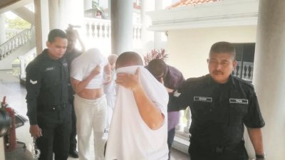 被告被警方押离法庭时遮著脸，以免被记者拍照。
