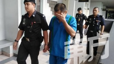 被告莫哈末苏克里（右）被带出法庭时，用手遮脸，闪避媒体镜头。（摄影：黄毓萍）
