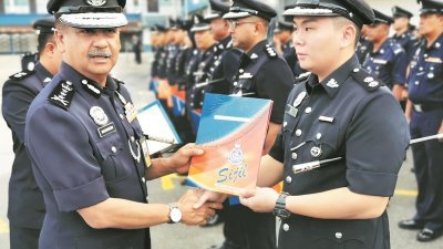 拉萨鲁丁（左）在霹雳州警察总部主持常月集会时，颁发表扬状予戴哲劲警长。